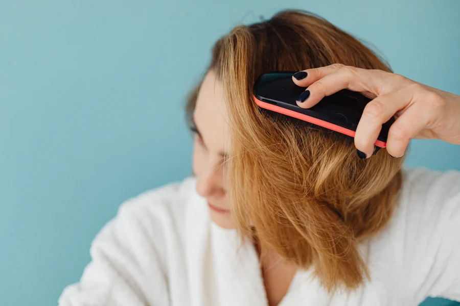 Femme brossant des cheveux secs avec une brosse en plastique, mèches soulevées