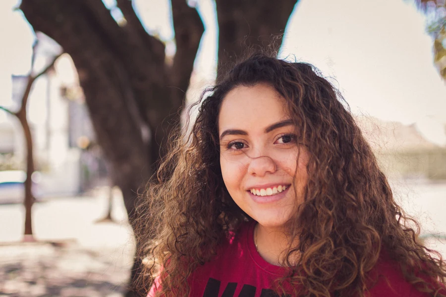 Jeune femme aux cheveux bouclés bien définis, en extérieur