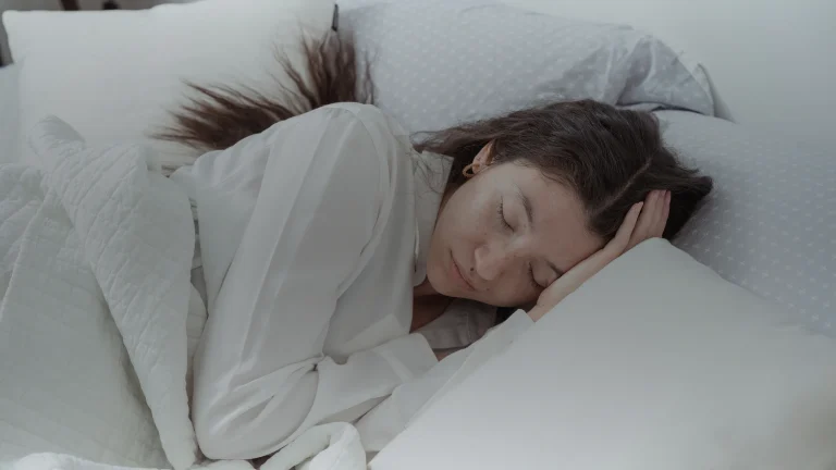 Femme endormie sur le côté, la tête sur un oreiller blanc