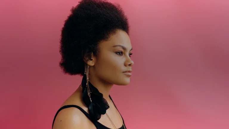 Profil d'une femme aux cheveux afro relevés sur fond rose