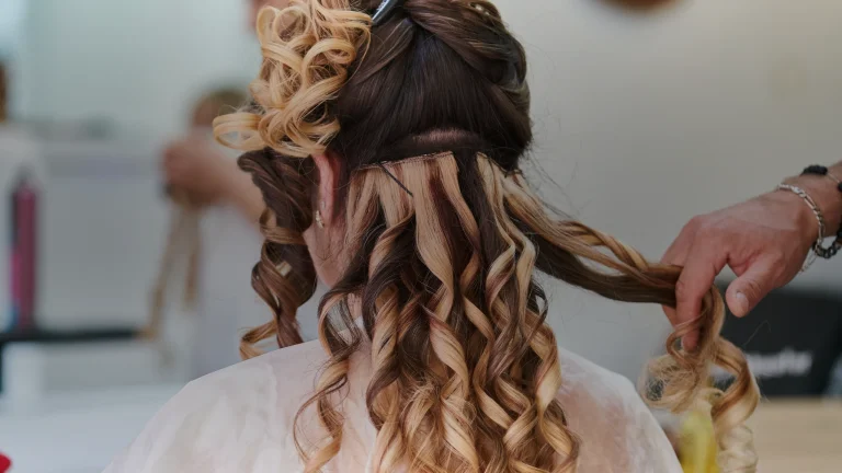 Une coiffeuse boucle une chevelure avec extensions