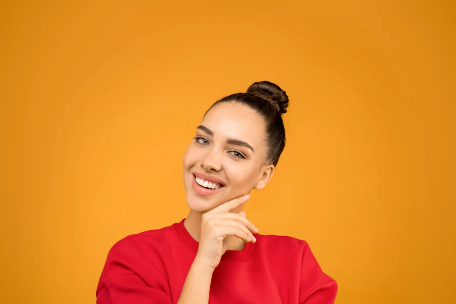 Femme aux cheveux tirés en chignon lisse et haut, vue de face
