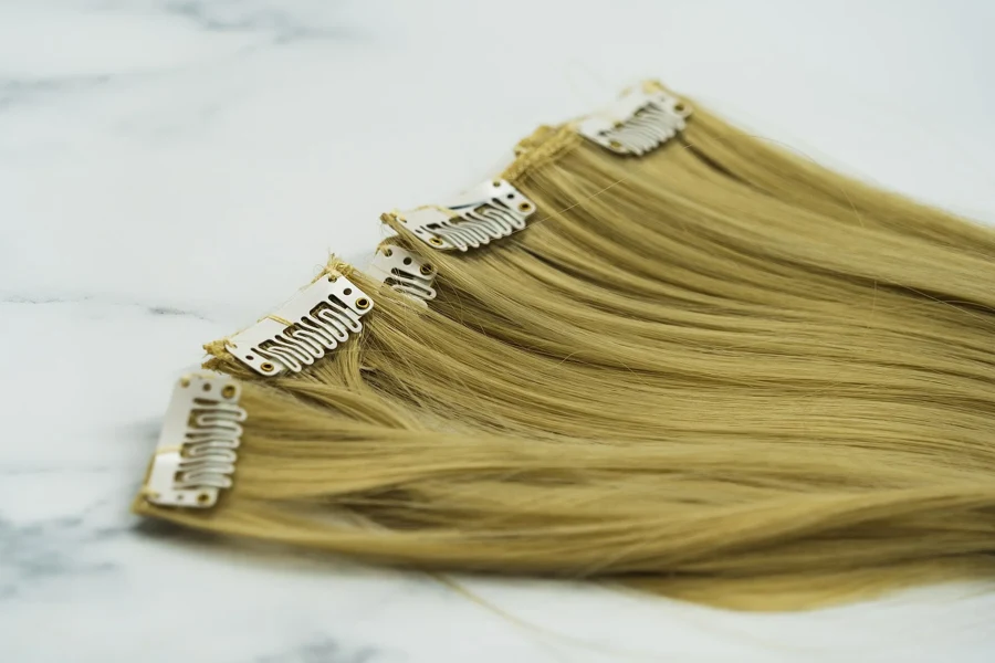 Mèches blondes à clips posées sur une surface claire